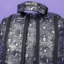 Load image into Gallery viewer, Close up of The Rustic Silver Spider Backpack sat on a purple background. The bag is facing away to highlight the two padded shoulder straps, the top handle and two elasticated side pockets. The vegan friendly faux leather bag has 3d embossed spiders in varying sizes with brushed black and silver tones all over.
