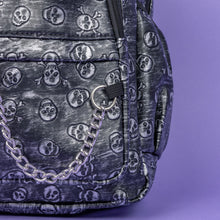 Load image into Gallery viewer, The Rustic Skulls Backpack sat on a purple background. A close up of the bag decorative silver chain detailing across the front. All over the backpack is an embossed 3d texture skulls and skull and crossbones on a faux leather material in a brushed black and silver grunge style.
