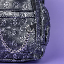 Load image into Gallery viewer, The Rustic Skulls Backpack sat on a purple background. A close up of the bag decorative silver chain detailing across the front. All over the backpack is an embossed 3d texture skulls and skull and crossbones on a faux leather material in a brushed black and silver grunge style.