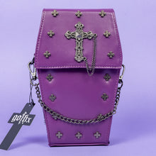 Load image into Gallery viewer, The GothX Purple Mini Coffin Bag sat facing forward on a lilac background. The coffin bag in a sleek faux leather is a coffin shape with a magnetic close clip flap with a cross chain emblem in the centre, surrounding the coffin shape is mini metal cross studs. Draping across the front of a silver detachable decorative chain with the GothX black cross tag hanging to the left side. 
