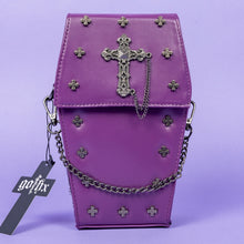 Load image into Gallery viewer, The GothX Purple Mini Coffin Bag sat facing forward on a lilac background. The coffin bag in a sleek faux leather is a coffin shape with a magnetic close clip flap with a cross chain emblem in the centre, surrounding the coffin shape is mini metal cross studs. Draping across the front of a silver detachable decorative chain with the GothX black cross tag hanging to the left side.