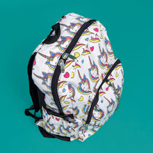 Load image into Gallery viewer, The Rainbow Unicorn Backpack sat facing forward angled right on a teal background. The vegan friendly backpack is a white canvas material with repeating kawaii cute unicorn heads with pink blue and yellow manes with hearts surrounding them. The bag is facing forward to highlight the front two zip pockets, the main zip compartment and silver draping decorative chain.