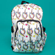 Load image into Gallery viewer, The Rainbow Unicorn Backpack sat facing forward on a teal background. The vegan friendly backpack is a white canvas material with repeating kawaii cute unicorn heads with pink blue and yellow manes with hearts surrounding them. The bag is facing forward to highlight the front two zip pockets, the main zip compartment and silver draping decorative chain.