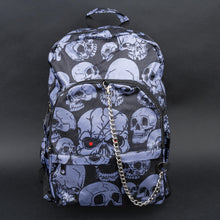 Load image into Gallery viewer, Full front view of grey skull backpack with chain and red eye detail – The complete front view of the backpack, showing the unique grey skulls against a dark background, accented with a silver chain and a bold red eye on one skull for an added gothic edge.
