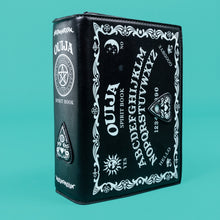 Load image into Gallery viewer, GothX Ouija Spirit Book Mini Bag on a teal background. The bag is sideways to show the ouija white print detail on the bag front and spine with 3D planchette stitching. Bag inspired by witchy style and necromancy.
