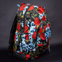 Load image into Gallery viewer, Side view of skull and rose print backpack with multiple compartments – Side angle showing the spacious compartments of the backpack, covered in a red rose, blue skull, and gold vine design. The side pocket and chain detail complete the gothic look.