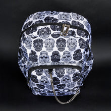 Load image into Gallery viewer, Front view of a gothic sugar skull backpack by CHOK GothX. This white bag with black skull prints is equipped with multiple compartments and silver chain embellishment, combining practical storage with a striking alternative aesthetic.