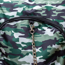 Load image into Gallery viewer, Close up of the Classic Camouflage vegan backpack with chain hanging on a brick wall. The backpack with a green and brown camo print is facing forward highlighting the two front zip pockets, two side pockets and silver decorative chain.