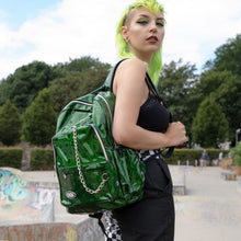 Load image into Gallery viewer, Model wearing the CHOK Green Holographic Hive Vegan Backpack with checkerboard trousers and green hair. They have the bag hanging on one shoulder to show off the adjustable shoulder strap and chain detailing.