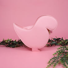 Load image into Gallery viewer, The kawaii pink glitter dino vegan bag on a pink studio background with green foliage. The vegan friendly pink leather sparkly cute bag is facing away from camera to highlight the detachable strap and plain pastel pink back.