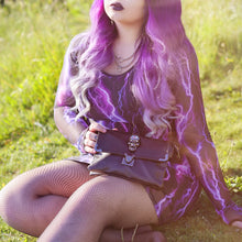 Load image into Gallery viewer, Model wearing a goth black and purple outfit holding the gothx crystal skull vegan shoulder bag on a grass field.