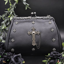 Load image into Gallery viewer, The GothX Don't Cross Me Vegan Vintage Clasp Handbag on a black studio background with black roses and green foliage surrounding it. The bag is facing forward to highlight the floral metal detailing along the top, vintage ball clasp close, mini cross studs and large cross chain emblem.