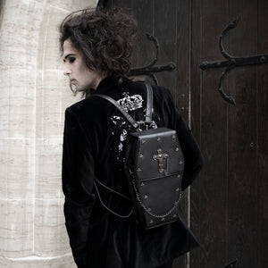 Sweeney wearing a goth outfit and the gothx coffin vegan backpack on their back. They are facing away from the camera to highlight the cross mini studs, cross and chain emblem and detachable silver chain.