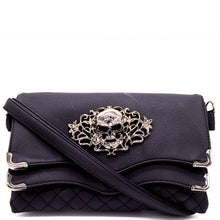 Load image into Gallery viewer, The GothX Skulls and Roses Quilted Clutch Bag shown on a white studio background with the detachable strap wrapped round the front. The vegan leather clutch bag is facing forward and being opened to highlight the two magnetic clip close flaps with metal corners, a stitch quilted front, a skulls and roses metal centrepiece and two D rings on either side for a detachable strap. The mini bag is inspired by gothic grunge witchy fashion.