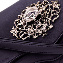 Load image into Gallery viewer, Close up of The GothX Skulls and Roses Quilted Clutch Bag shown on a white studio background with the detachable strap wrapped round the front. The vegan leather clutch bag is facing forward and being opened to highlight the two magnetic clip close flaps with metal corners, a stitch quilted front, a skulls and roses metal centrepiece and two D rings on either side for a detachable strap. The mini bag is inspired by gothic grunge witchy fashion.