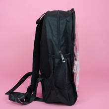 Load image into Gallery viewer, The Kawaii Black & Clear Window Vegan Ita Backpack on a pastel pink background. The bag is facing right filled with pastel confetti and pom poms to highlight the clear display window, double zip opening, side pockets and padded adjustable shoulder straps.