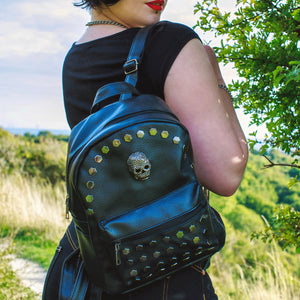 Model wearing the gothx skull head large studs vegan mini backpack on one shoulder with a goth outfit and red lipstick. 