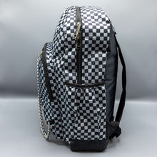 Load image into Gallery viewer,  The Grey Checkerboard Backpack sat on a grey background. The vegan friendly bag is facing left to highlight the grey and black check print, two front zip pockets, two elasticated side pockets, main top double zip pocket and silver draping decorative chain.