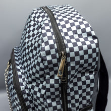 Load image into Gallery viewer, Close up of the Grey Checkerboard Backpack sat on a grey background. The vegan friendly bag is facing forward to highlight the grey and black check print, two front zip pockets, two elasticated side pockets, main top double zip pocket and silver draping decorative chain.