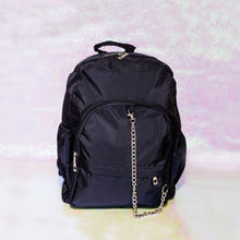 Load image into Gallery viewer, The black nylon vegan backpack with chain on an iridescent background. The bag is facing forward to highlight the two front zip pockets, two side pockets, double zip main compartment, top handle and detachable silver chain.
