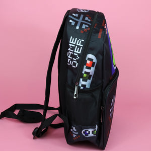 The black game over vegan backpack on a pink studio background. The bag is facing right to highlight the front game boy inspired print with printed green game over screen and gaming button controls on the front zip pocket and side pockets.