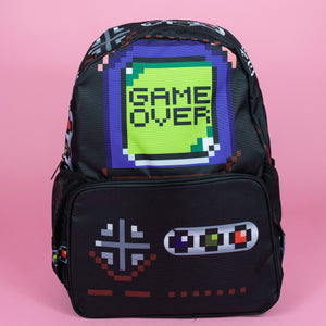 The black game over vegan backpack on a pink studio background. The bag is facing forward to highlight the front game boy inspired print with printed green game over screen and gaming button controls on the front zip pocket and side pockets.