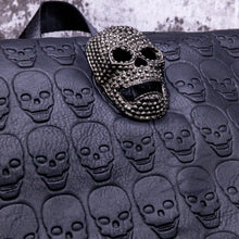 Load image into Gallery viewer, Close up of the diamante effect silver skull head on a skull embossed vegan leather flap on the gothx twin pocket skull vegan backpack.