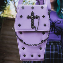 Load image into Gallery viewer, The GothX Pastel Lilac Mini Coffin Vegan Cross Body Bag being held up by a gothic alternative model. The vegan friendly pastel leather bag is facing forward to highlight the cross studs, cross & chain centrepiece, detachable chain and detachable adjustable shoulder strap.