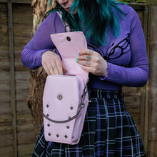 Load image into Gallery viewer, GothX Pastel Pink Mini Coffin Vegan Cross Body Bag being held up by an alternative goth model. The bag being opened up to show the magnetic clip close flap, the detachable chain and stud detailing.