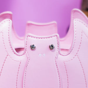 Close up of the front embroidered and crystal eye detailing of the GothX Pastel Pink Bat Vegan Shoulder Bag in front of a pastel purple background.
