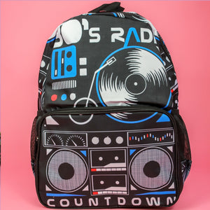 The retro black 80s stereo vegan backpack on a pink background. The bag is facing forward to highlight the 80s stereo boombox front print, front zip pocket, main zip compartment, two side pockets and top handle.