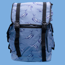 Load image into Gallery viewer, The Blue Swordfish Vegan backpack on a blue studio background. A pastel blue backpack with black buckle and strap detailing with swordfish printed all over. The bag is facing forward open to highlight the side buckle pockets, drawstring and buckle close and black piping detailing.