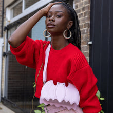 Load image into Gallery viewer, GothX Pastel Pink Bat Vegan Shoulder Bag being held by an alternative model wearing a pastel goth outfit. The bag is facing forward to highlight the embroidered detailing, silver faux crystal eyes and detachable adjustable strap.
