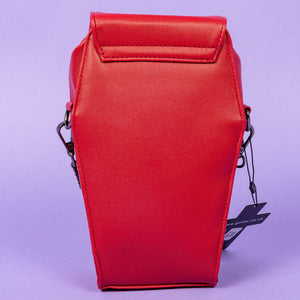 The GothX Red Mini Coffin Bag facing away on a purple background to highlight the plain back. The coffin bag is made with vegan friendly sleek red leather features a magnetic clip close flap with a zip compartment and detachable, adjustable strap.