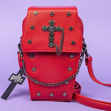 Load image into Gallery viewer, The GothX Red Mini Coffin Bag facing forward on a purple background. The coffin bag is made with vegan friendly sleek red leather and features a detachable decorative metal chain with a large metal cross and chain emblem with surrounding cross studs. The detachable adjustable strap is sat folded up next to the mini bag.
