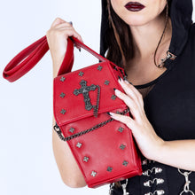 Load image into Gallery viewer, A gothic styled model with dark vampy red makeup wearing a goth black hooded dress holding the GothX Red Mini Coffin Bag to their chest on a white background. The coffin bag is made with vegan friendly sleek red leather and features a detachable decorative metal chain with metal cross studding.
