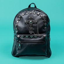 Load image into Gallery viewer, The GothX black cross vegan stud mini backpack on a teal background. The vegan leather bag is facing forwards to highlight the cross studs along the top zip line and top of zipped pocket, studded cross with chain centrepiece and side metal cross studs on the slot pockets.
