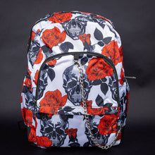 Load image into Gallery viewer, Full front view of white skull and rose backpack with chain accent – A full front view of the backpack, featuring a bold black skull and red rose design against a white background, with a silver chain detail on the front pocket for an extra edgy touch.
