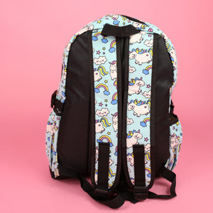 The kawaii unicorn vegan backpack sat on a pink background. The bag is facing away to highlight the pastel blue rainbow unicorn print on the padded adjustable shoulder straps, two side pockets, top handle and plain black back.