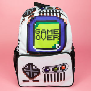 The white game over vegan backpack on a pink studio background. The bag is facing forward to highlight the front game boy inspired print, front zip pocket and side pockets. The backpack features a 90s inspired gameboy print with buttons and a screen saying game over.