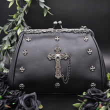 Load image into Gallery viewer, The GothX Don&#39;t Cross Me Vegan Vintage Clasp Handbag on a black studio background with black roses and green foliage surrounding it. The bag is facing forward to highlight the floral metal detailing along the top, vintage ball clasp close, mini cross studs and large cross chain emblem.
