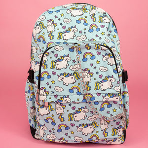 The kawaii unicorn vegan backpack sat on a pink background. The bag is facing forward to highlight the pastel blue rainbow unicorn print, two front zip pockets, two side pockets and detachable silver chain.