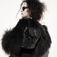 Load image into Gallery viewer, Model wearing a large black fluffy coat and sunglasses holding the goth dont cross me vegan tassel tie backpack on one shoulder. The bag is facing the camera to show the cross, skull &amp; hexagon studs, tassel tie close and the cross chain emblem magnetic clip close flap.
