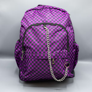 The Purple Checkerboard Backpack sat on a grey background. The vegan friendly bag is facing forward to highlight the purple and black check print, two front zip pockets, two elasticated side pockets, main top double zip pocket and silver draping decorative chain.