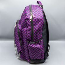 Load image into Gallery viewer, The Purple Checkerboard Backpack sat on a grey background. The vegan friendly bag is facing left to highlight the purple and black check print, two front zip pockets, two elasticated side pockets, main top double zip pocket and silver draping decorative chain.
