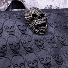 Load image into Gallery viewer, Close up of the diamante effect silver skull head on a skull embossed vegan leather flap on the gothx twin pocket skull vegan backpack.
