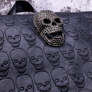 Close up of the diamante effect silver skull head on a skull embossed vegan leather flap on the gothx twin pocket skull vegan backpack.
