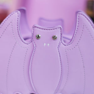 Close up of the front embroidered and crystal eye detailing of the GothX LIMITED EDITION Pastel Lilac Purple Bat Vegan Shoulder Bag in front of a pastel purple background.