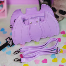 Load image into Gallery viewer, The GothX LIMITED EDITION Pastel Lilac Purple Bat Vegan Shoulder Bag on a pastel purple background with multicoloured confetti, pastel pink coffin shelving and black skull bottles surrounding it. The bag is facing forward to highlight the embroidered detailing, crystal eyes and detachable adjustable strap.
