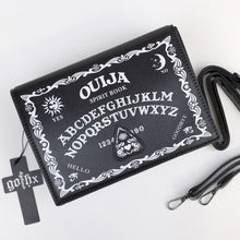 Load image into Gallery viewer, The GothX Ouija Spirit Book Mini Bag sat on a white background. The bag is forward to highlight the ouija spirit book white printed detailing on the black book bag with the 3D planchette stitching. Next to the bag on the right is the adjustable detachable strap. Bag is inspired by witchy style and necromancy.
